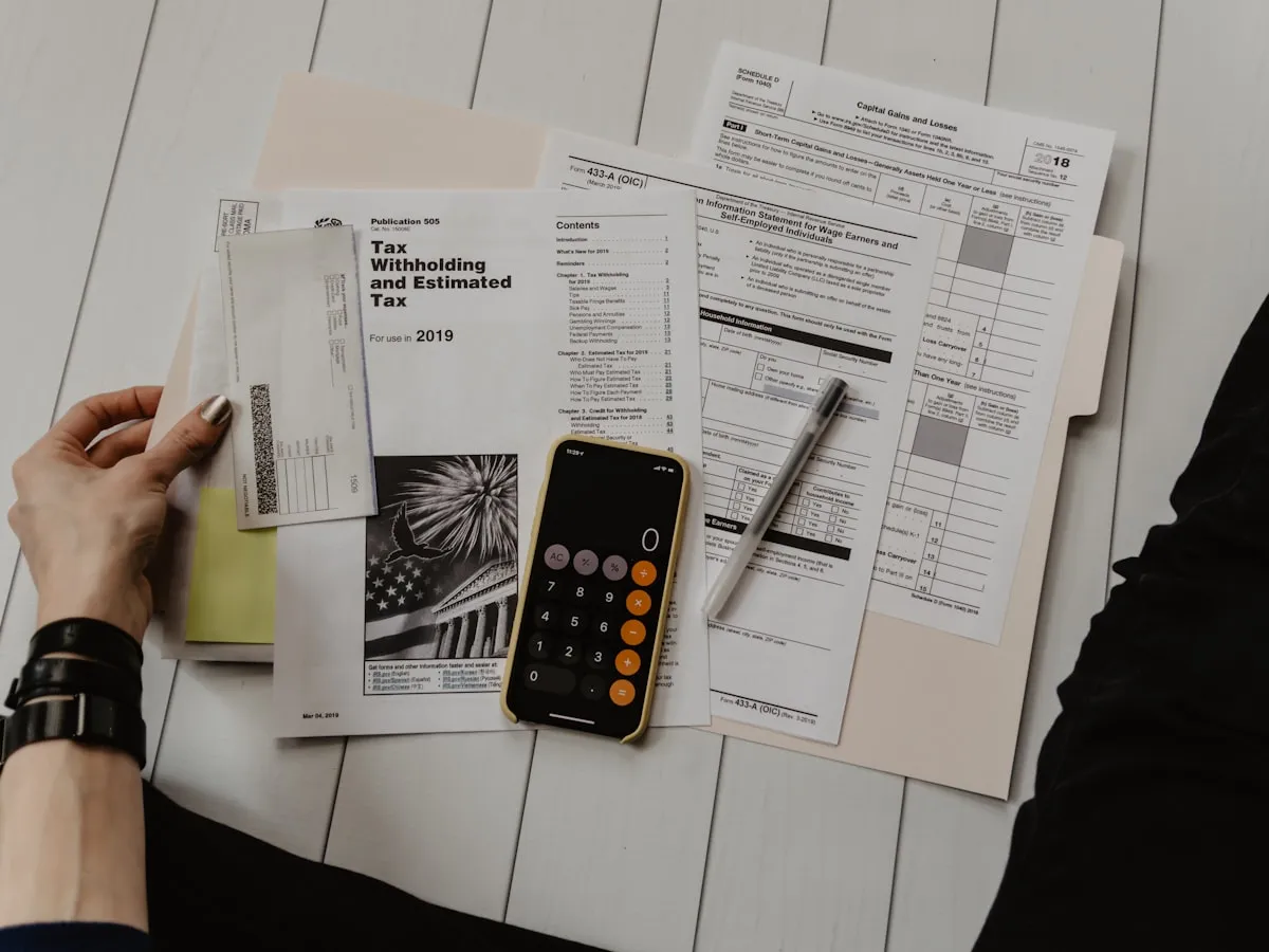 Une dirigeante de petite entreprise examine une facture et des documents à un bureau avec un ordinateur portable et une calculatrice